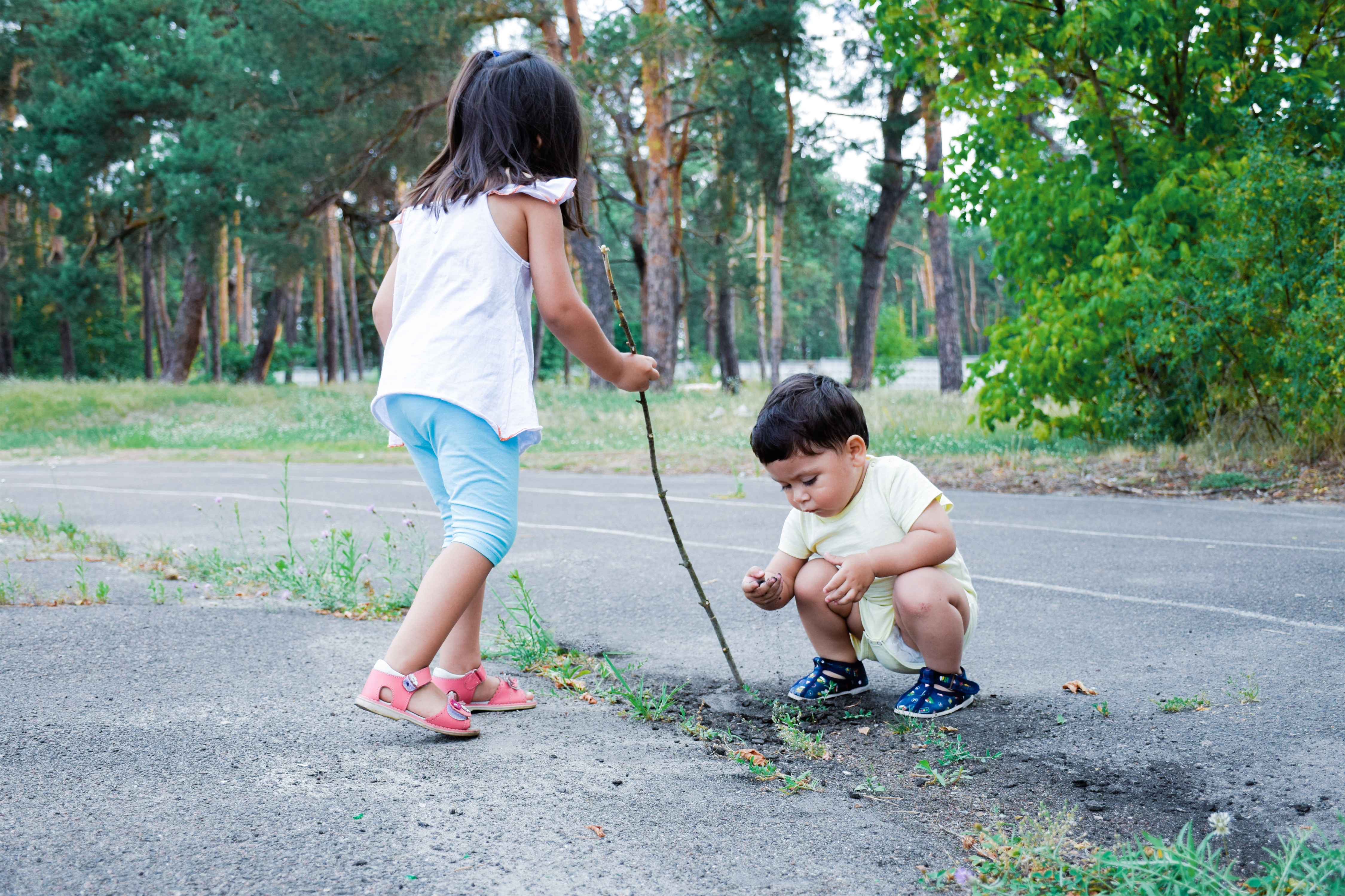 two children exploring outside with sticks